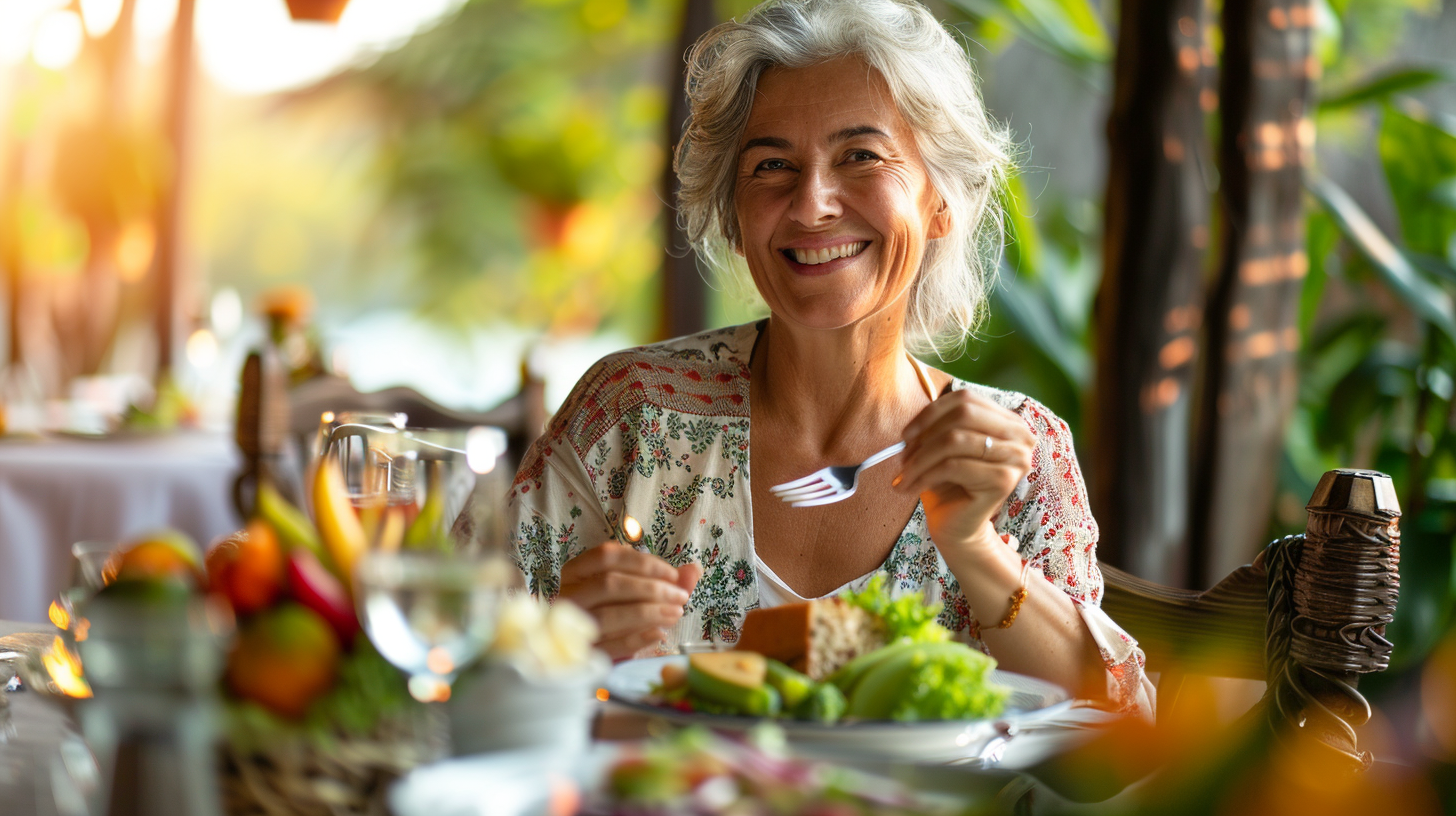 A smiling woman in her mid 50's eating a healthy meal.