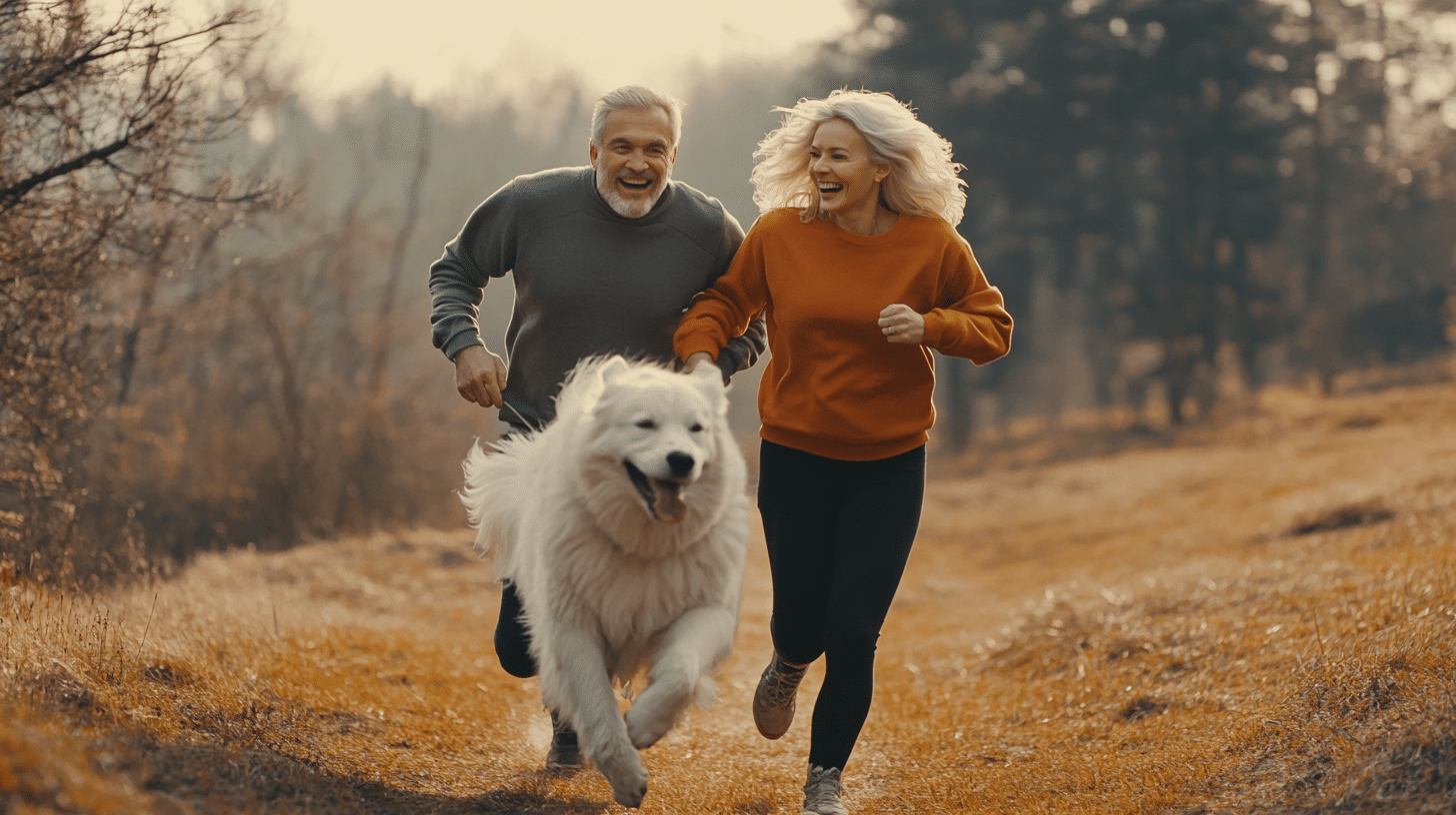 A couple jogging in the forest with their dog.